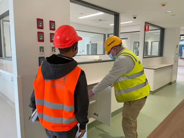 A Blue Cleaning worker and a builder in a Hansen Yuncken vest checking inside a joinery cabinet